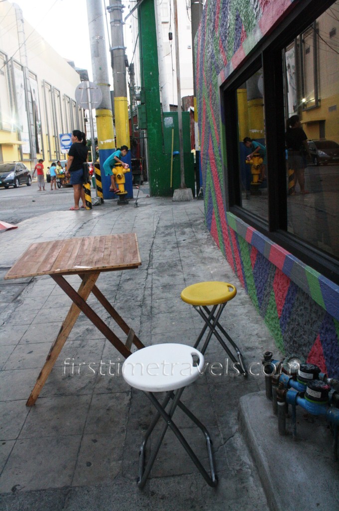 Tables and chairs are placed at the street outside of the hostel.