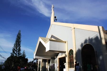 A pine tree outside and residences surrounding the church give it a homey feel.